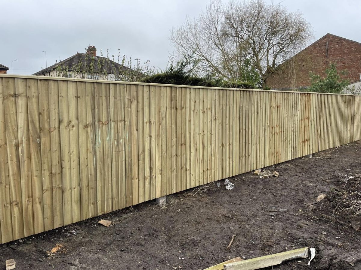 Long run of new close-board feather-edge fencing with capping rail