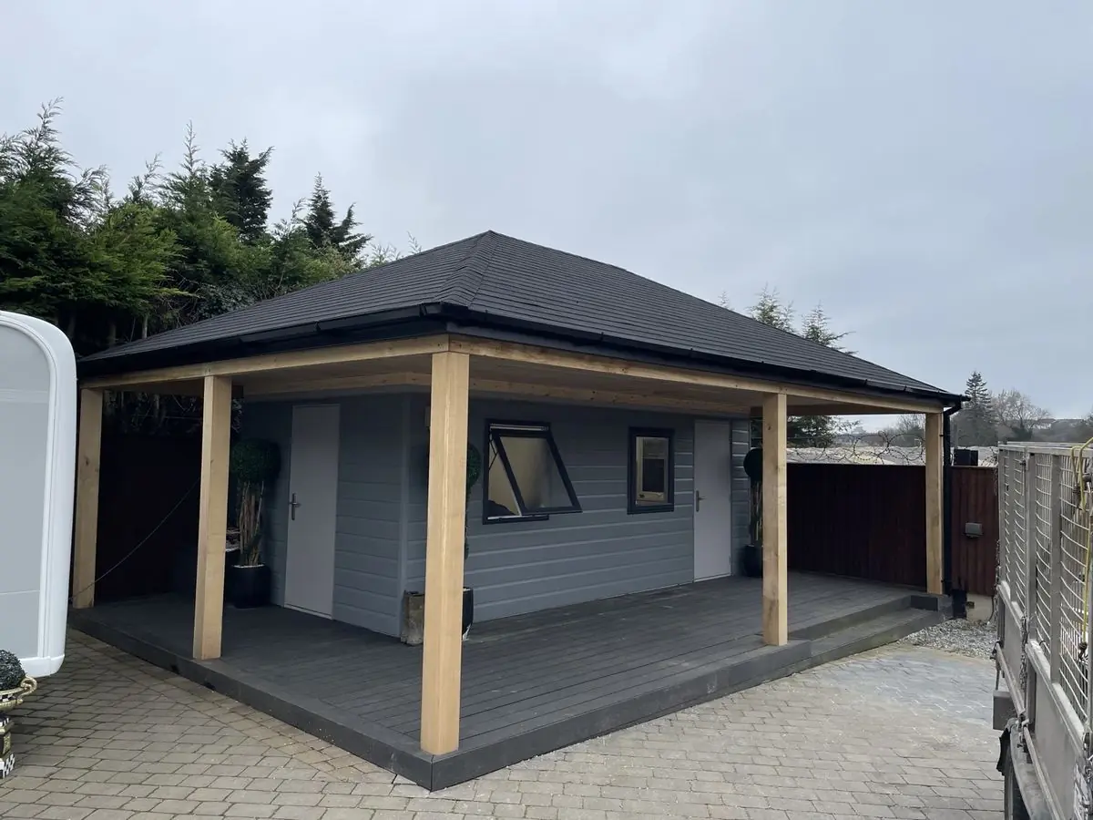 Bespoke garden room with a covered oak-post veranda and slate-grey hipped tiled roof on a paved base
