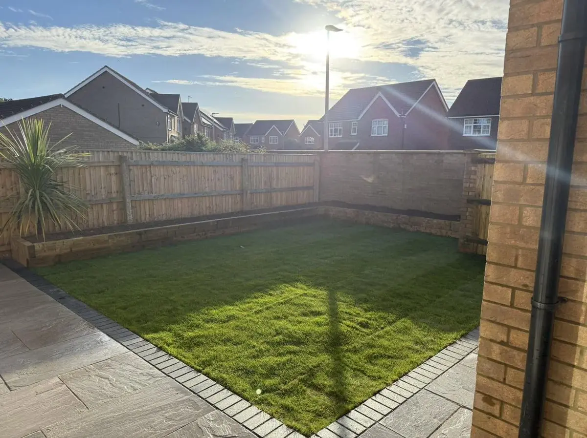 Landscaped garden with sandstone patio, lawn and new fencing at sunset