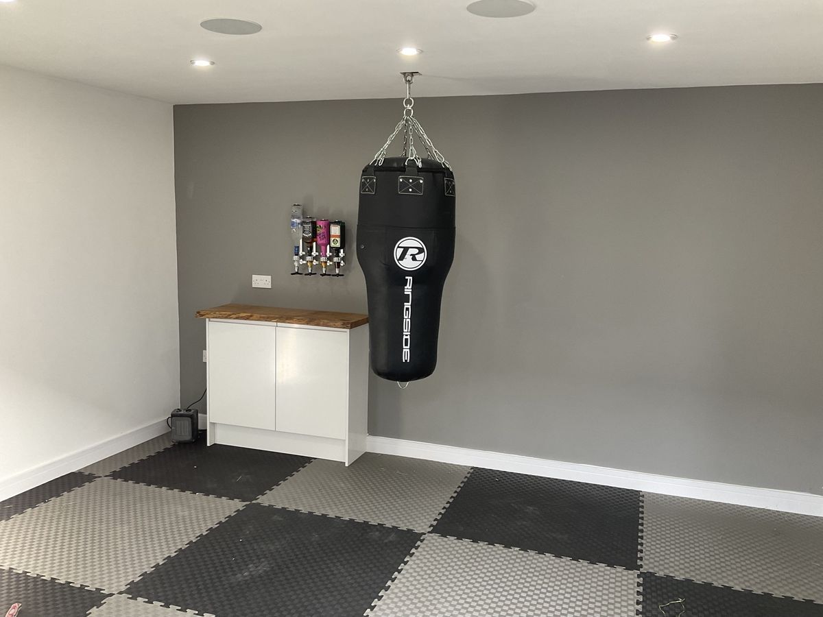 Garage converted into a home gym with fitted units and rubber-tiled floor
