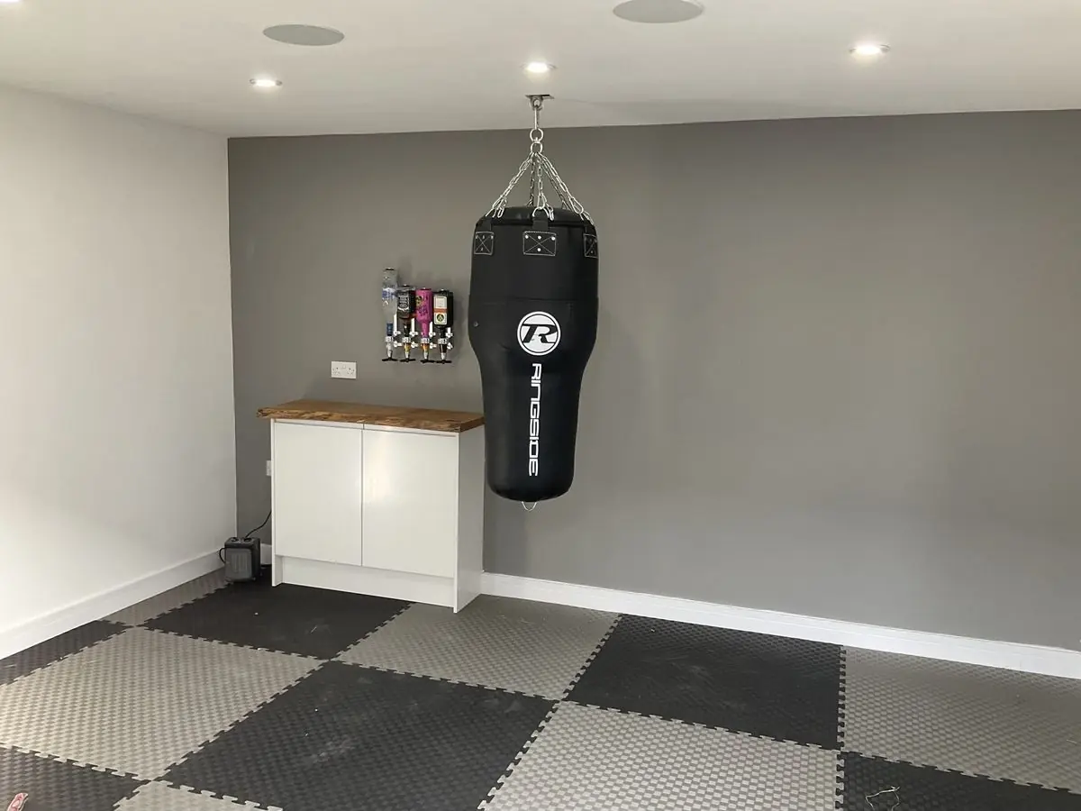 Garage converted into a home gym with fitted units and rubber-tiled floor